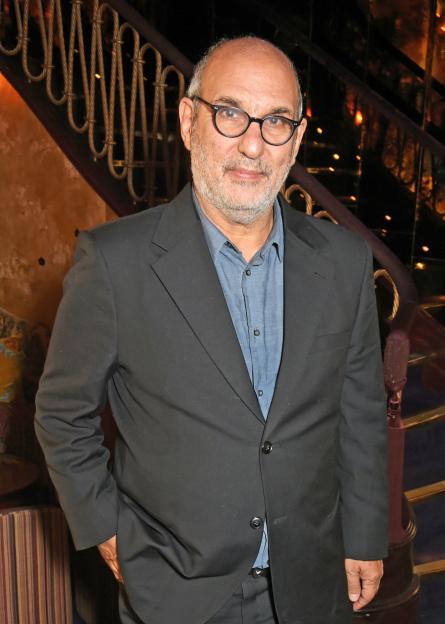 Alan Yentob in a black suit jacket and blue shirt, posing for a photo at an event.