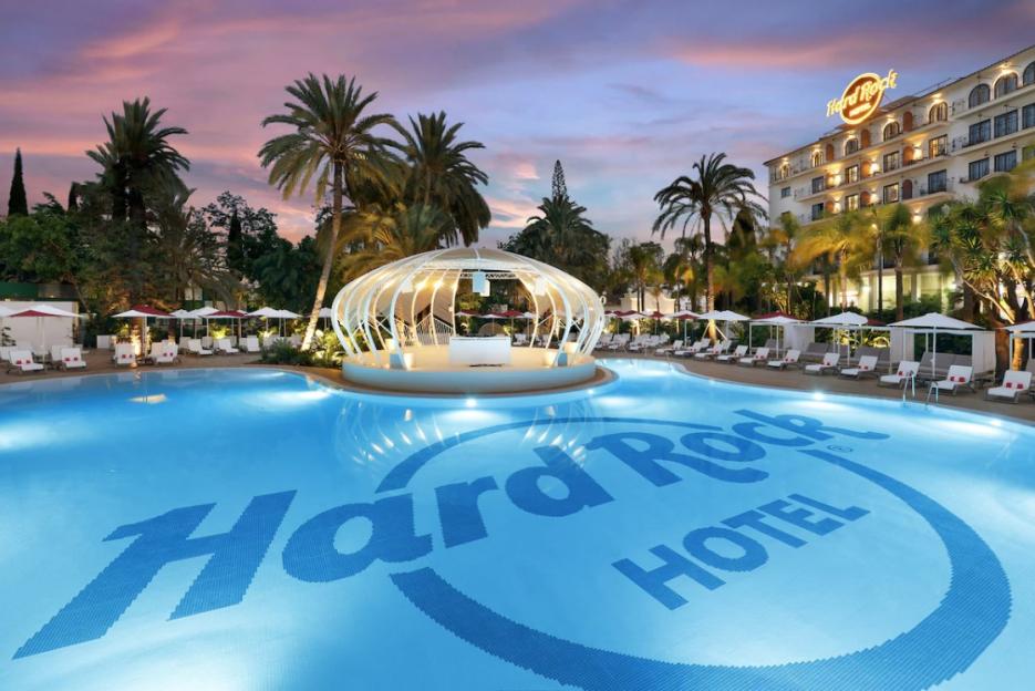 The Hard Rock Hotel with a large outdoor pool and white cabanas at sunset.