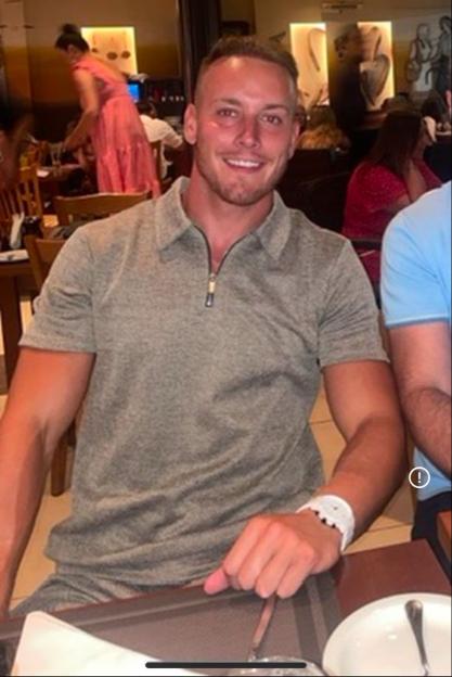 A man in a gray polo shirt smiling at a restaurant.