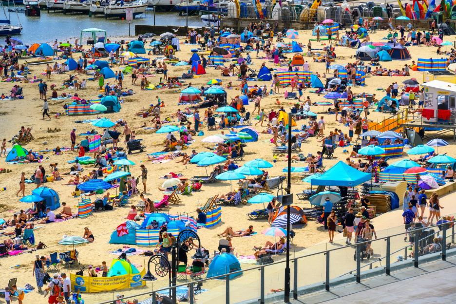 Families and holidaymakers enjoying a sunny day on the beach at Lyme Regis.