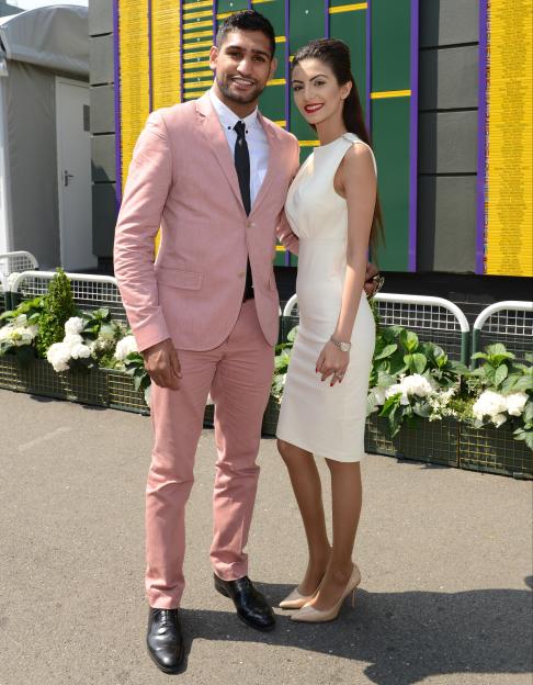 Amir Khan and Faryal Makhdoom posing in front of a Wimbledon “Gentlemen’s Singles” scoreboard.