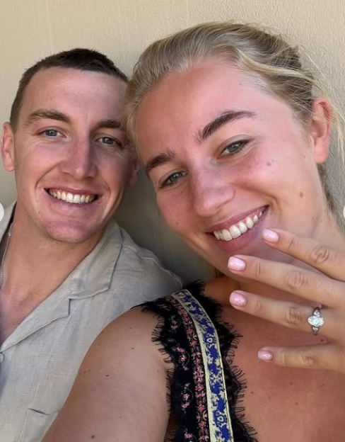 A happy couple with the woman showing off her engagement ring.