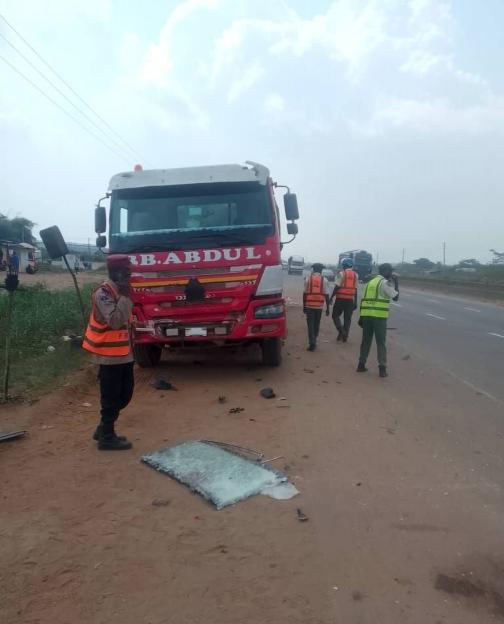 Road Safety Corps officers at the scene of a crash involving a red truck and another vehicle.