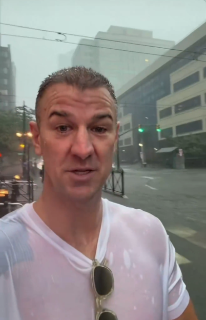 Man with wet hair and white shirt standing in flash flood.