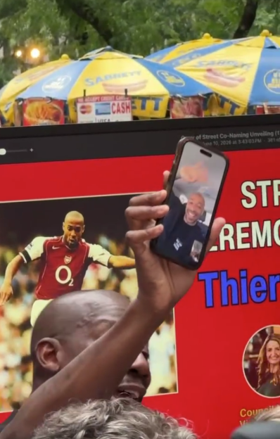 A person holding up a phone with Thierry Henry on a video call, superimposed over a street co-naming ceremony sign featuring a younger Thierry Henry in an Arsenal jersey.