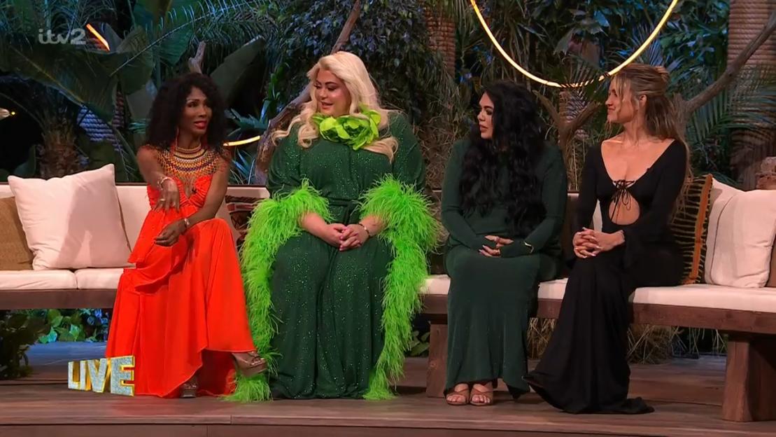 Four women in formal attire sit on a bench during a live broadcast.