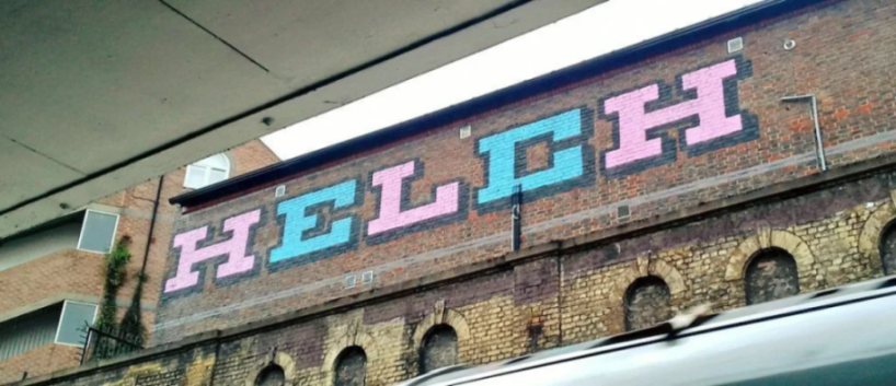 The word "HELCH" spray-painted in pink and blue block letters on a brick wall.