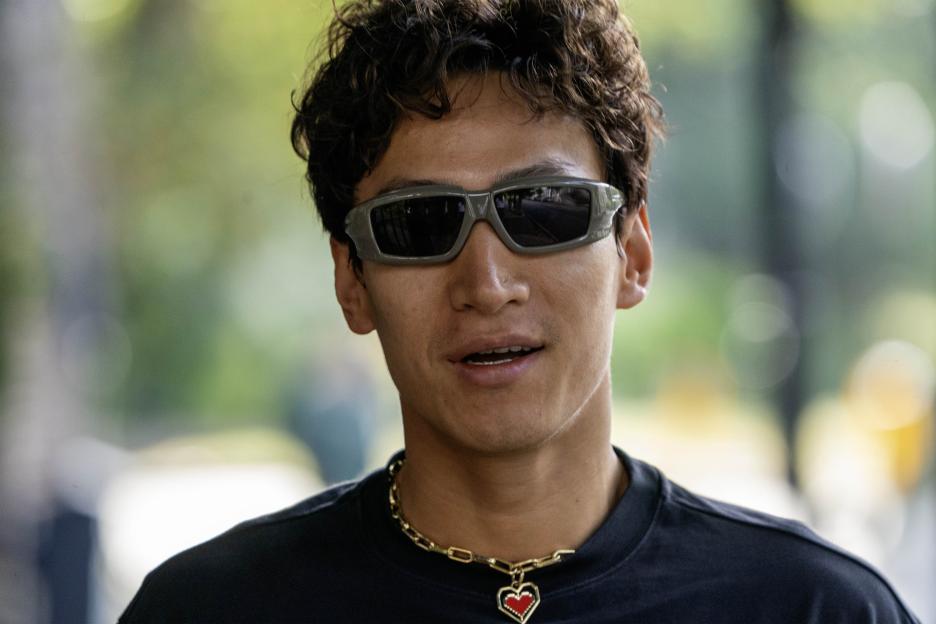 Strictly dancer Carlos Gu wearing sunglasses and a gold chain with a heart pendant.