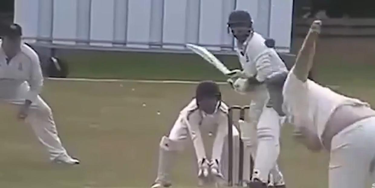 A cricket bowler in action on the right, with a batsman and wicketkeeper on the left.