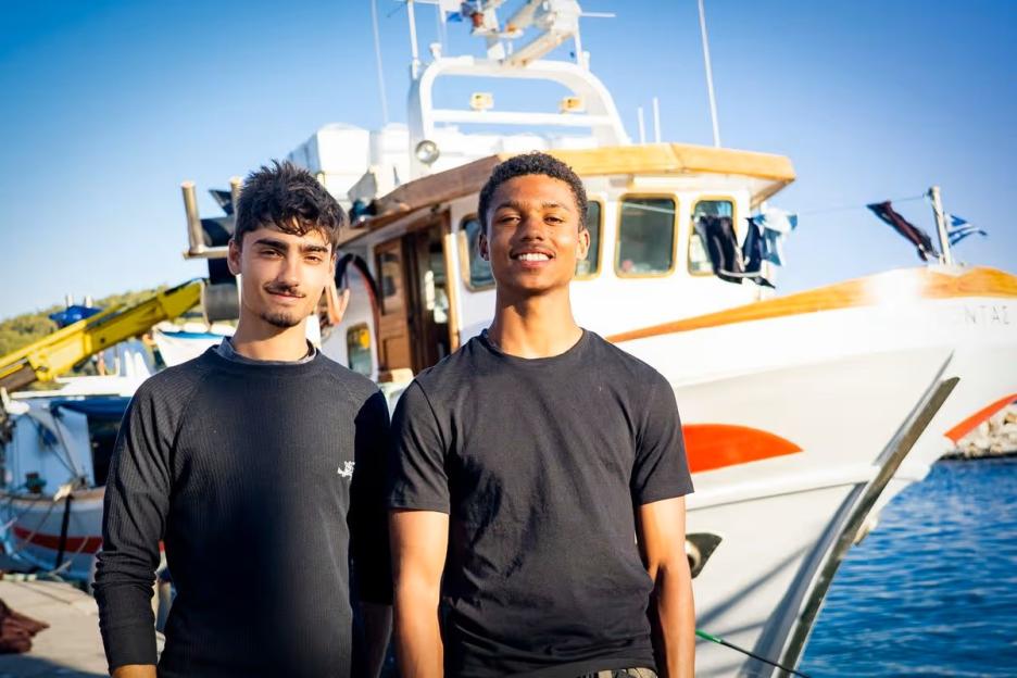 Jo and Kush standing in front of a boat.