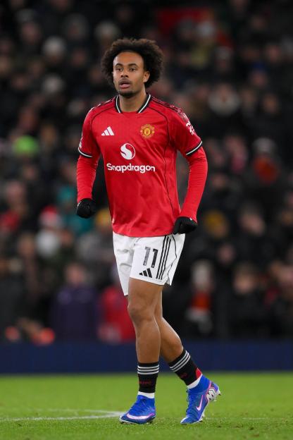 A photo of a Manchester United player in a red jersey and white shorts with the number 11 on them, standing on a green field.