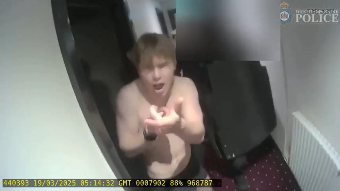 Johannes Natland, shirtless, pretending to shoot an armed officer during his arrest.