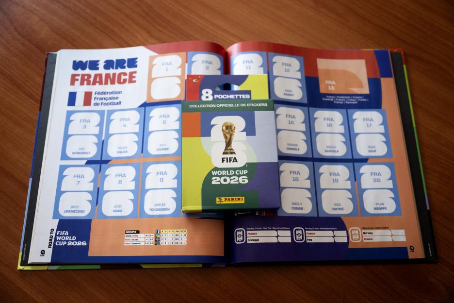 A FIFA World Cup 2026 Panini sticker album open to the French team's pages, with an unopened pack of stickers on top.