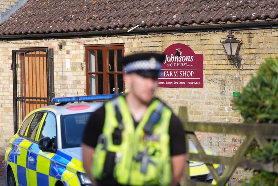 Police officer and vehicle outside Johnson's of Old Hurst farm shop, following an incident.