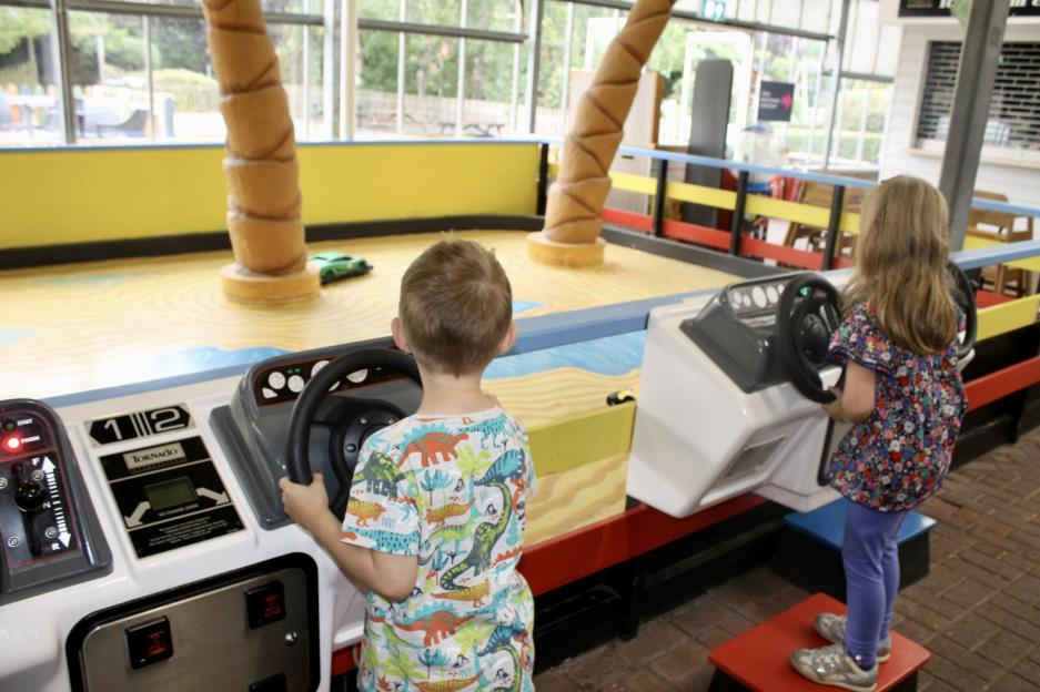 Two children playing a racing arcade game.