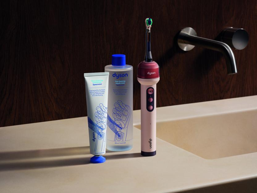 Dyson electric toothbrush, toothpaste, and mouthwash on a bathroom counter.