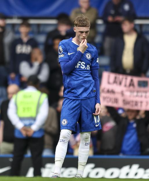 Cole Palmer of Chelsea looking down with a hand to his mouth after his team's defeat.
