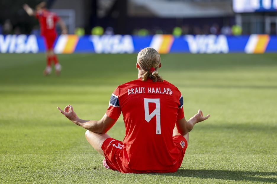 Erling Haaland meditating on the field after scoring his team's first goal.
