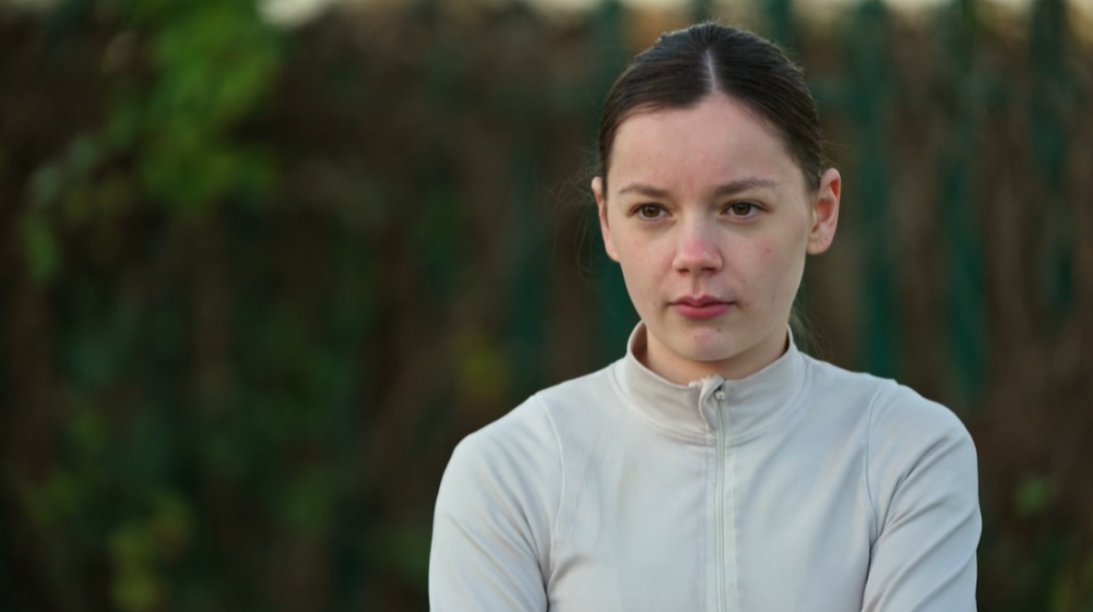 Ellie Radford, 20, dressed in a light grey athletic top, looking serious.