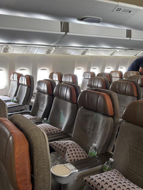 An airplane cabin with rows of empty seats, each with a pillow and a bottle of water.