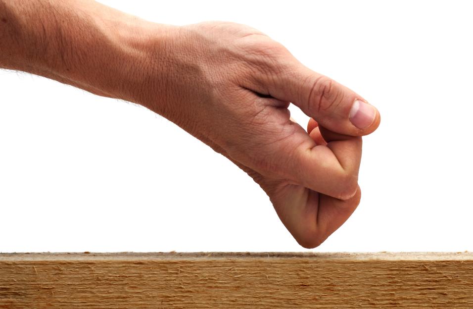 A person's fist knocking on a piece of wood.