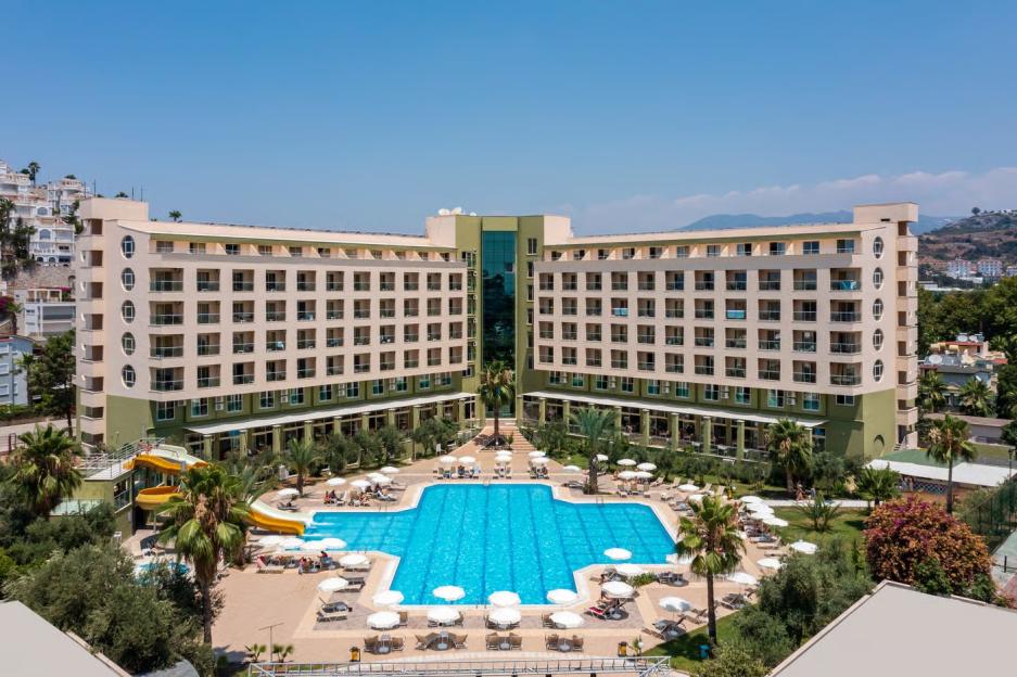 Aerial view of a large resort hotel with a pool area, water slides, and palm trees.