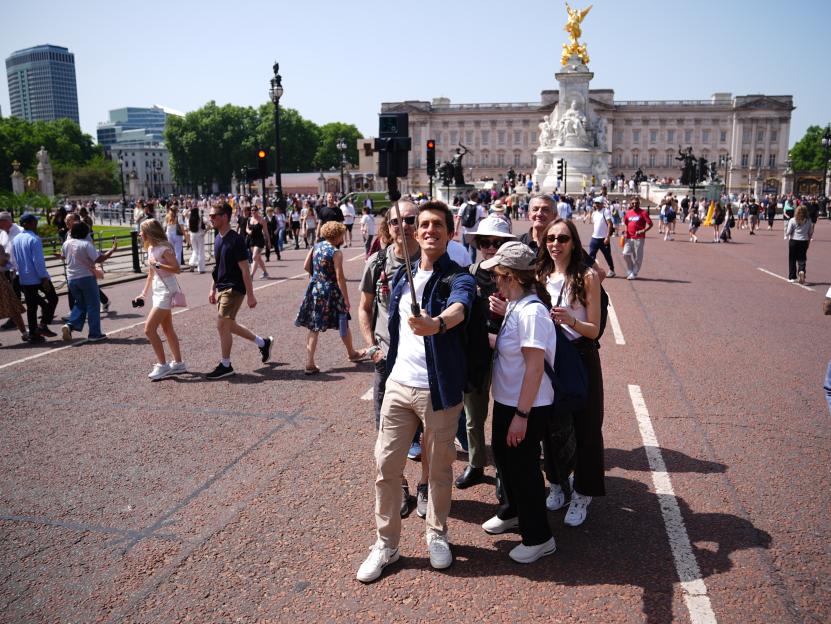 Tourists take a selfie in front of the Queen Victoria Memorial at Buckingham Palace.