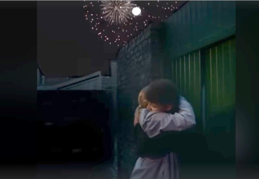 Two people embracing under a display of fireworks.