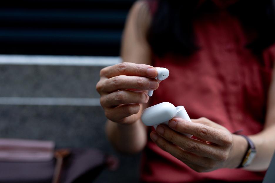 Person taking wireless earbuds from charging case.