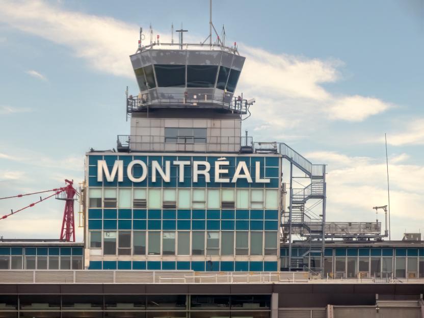 Close-up of the Montreal-Trudeau Airport control tower with the city name on its blue facade.