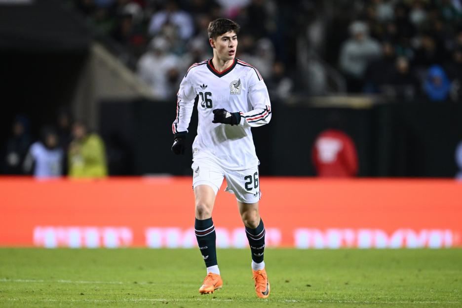 A soccer player in a white and green Mexico uniform with the number 26 on it.
