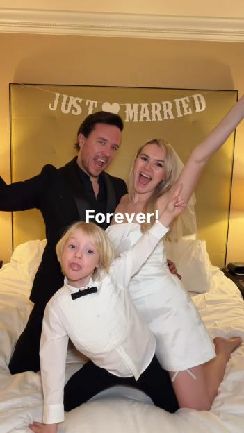 A man, woman, and child celebrating a wedding with a "Just Married" banner in the background.