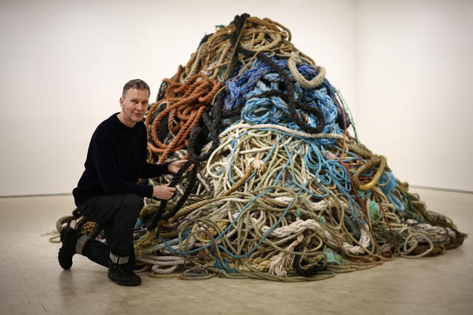 Artist David Shrigley poses next to his "Exhibition of Old Rope" installation.