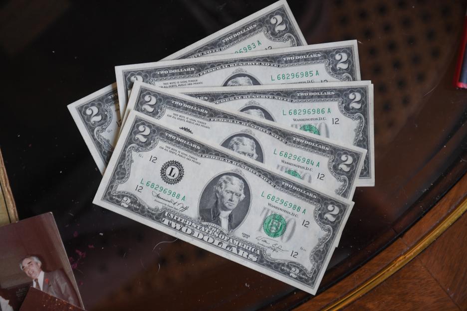 A stack of U.S. two-dollar bills, with Thomas Jefferson's portrait visible on the top bill.