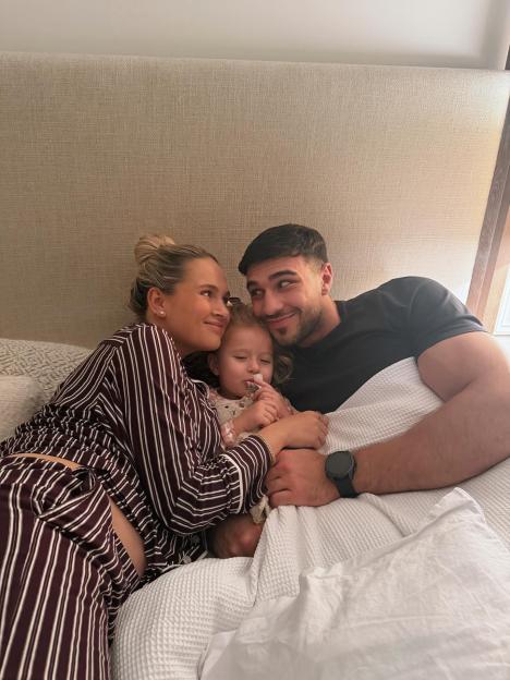 Molly Mae with her partner and child in bed, showing her growing baby bump.