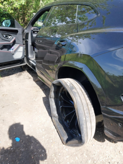 A black car with a flat, shredded tire.