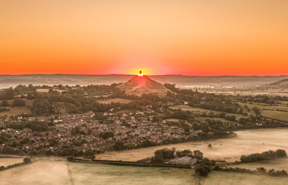 A sunrise over Glastonbury Tor and the surrounding mist-filled valley.