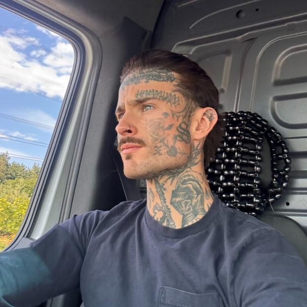 Brad North, heavily tattooed, looking out a car window.