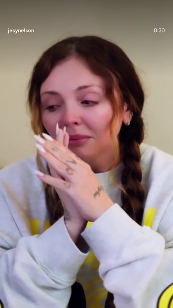 Jesy Nelson crying with her hands clasped.