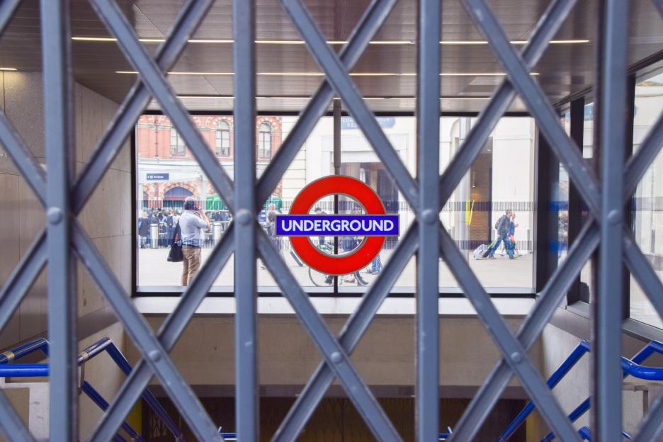 A closed underground station, with a metal gate blocking the entrance and the Underground logo visible through the gate.
