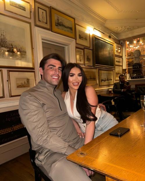 A man and a woman posing for a picture in a room with framed artwork on the walls.