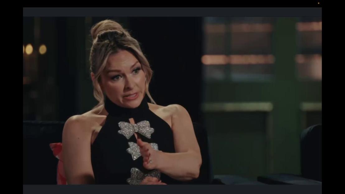 Mel Schilling, a woman in a black top with sparkly bow embellishments, gesticulating while speaking.
