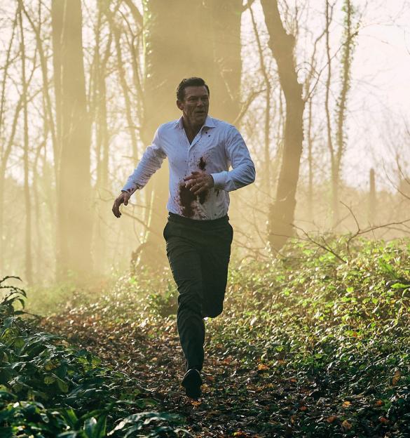 Luke Evans as Martin Gilmour, bloodied and running through a misty forest.