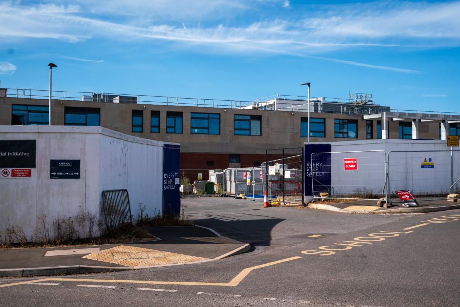 The Matford Brook Academy school building with construction fences and signs that read "Keep Out" and "Footpath Closed."