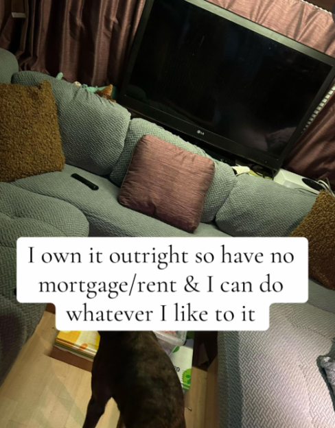 Living area inside a caravan with a TV and couch with pillows, and a dog partially visible at the bottom.