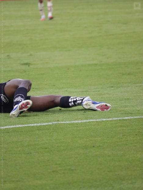 A soccer player lies on the grass field, injured or resting.