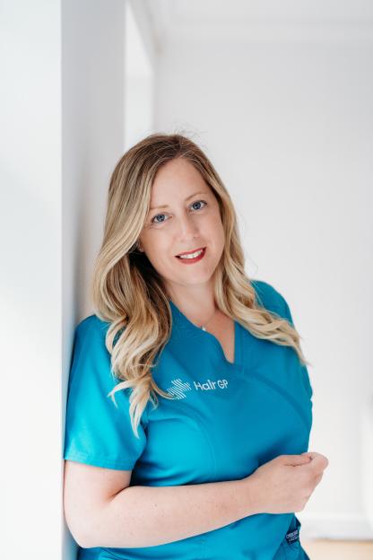 Amy from The Hair GP, a woman with long blonde hair, wearing a teal uniform.