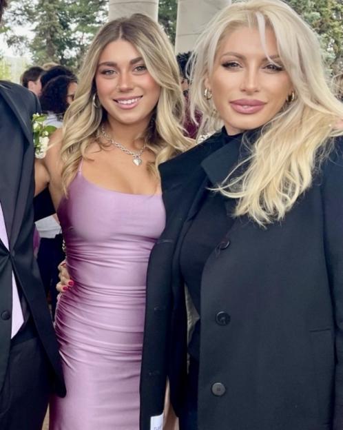 Two women, one in a lilac dress and one in a black coat.