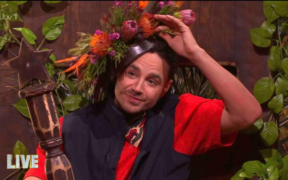 Adam Thomas wearing a crown of flowers and holding a star-shaped trophy.