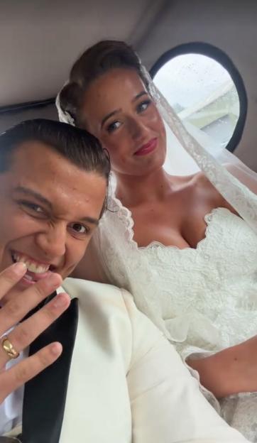 A man in a tuxedo and a woman in a white wedding dress in a car.